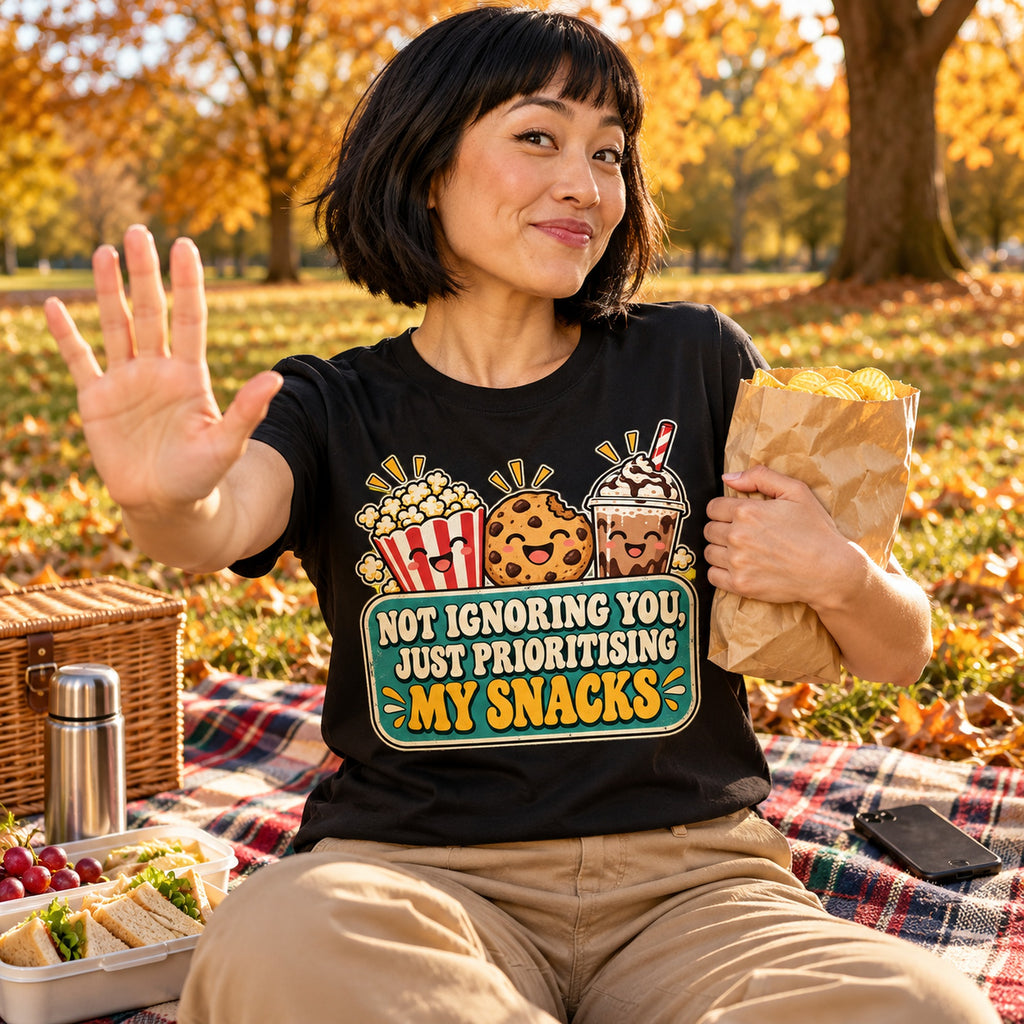 Woman wearing the Retro Snack Label design black t-shirt on a picnic blanket in an autumn park