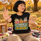 Woman wearing the Retro Snack Label design black t-shirt on a picnic blanket in an autumn park
