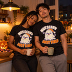 Couple wearing the Sleepy Ghost design black t-shirt in a cosy kitchen on Halloween night holding mugs