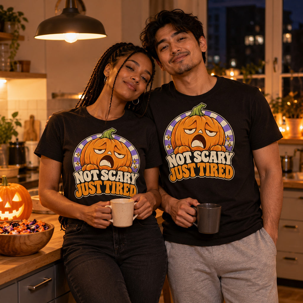 Couple wearing the Retro Pumpkin design black t-shirt in a cosy kitchen on Halloween night holding mugs