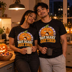 Couple wearing the Retro Pumpkin design black t-shirt in a cosy kitchen on Halloween night holding mugs