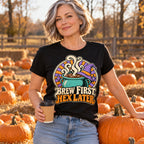 Woman wearing the Cauldron Badge design black t-shirt at an autumn pumpkin patch holding a coffee cup