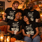 Group of friends wearing the Witch Hat Mug design black t-shirt at a cosy Halloween house party holding mugs