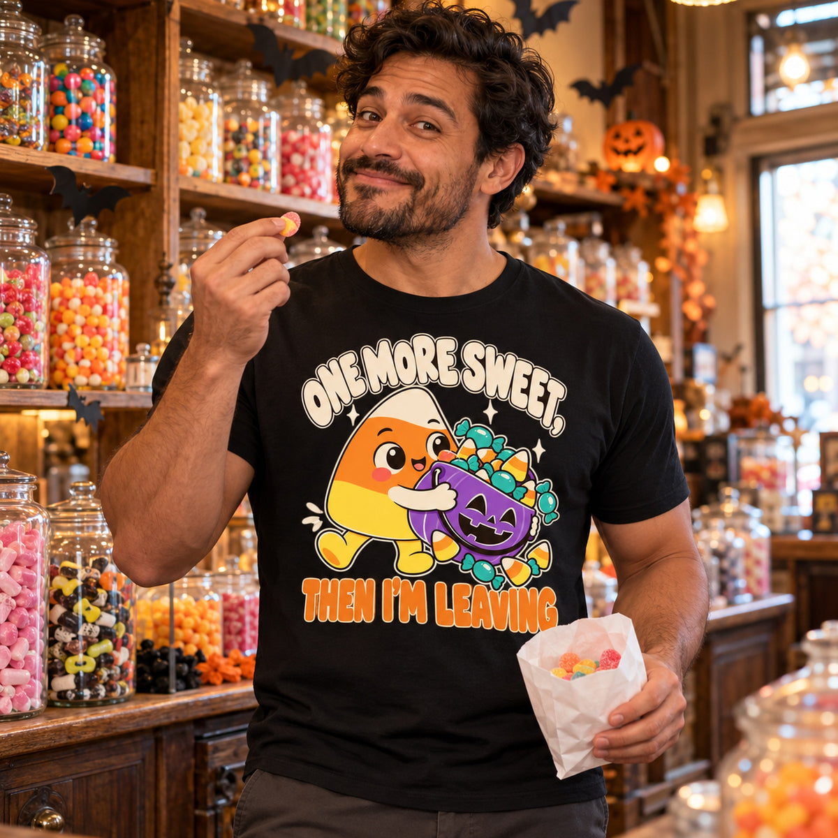 Man wearing the Candy Corn design black t-shirt in an old fashioned sweet shop holding a bag of sweets