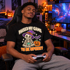 Man wearing the Pixel Skeleton Gamer design black t-shirt at a gaming desk in a bedroom with Halloween lights