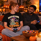 Couple wearing the Pixel Skeleton Gamer design black t-shirt on a sofa with controllers and Halloween pumpkins