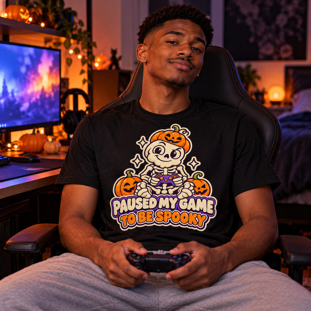 Man wearing the Sticker Skeleton Gamer design black t-shirt at a gaming desk in a bedroom with Halloween lights