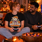 Couple wearing the Sticker Skeleton Gamer design black t-shirt on a sofa with controllers and Halloween pumpkins