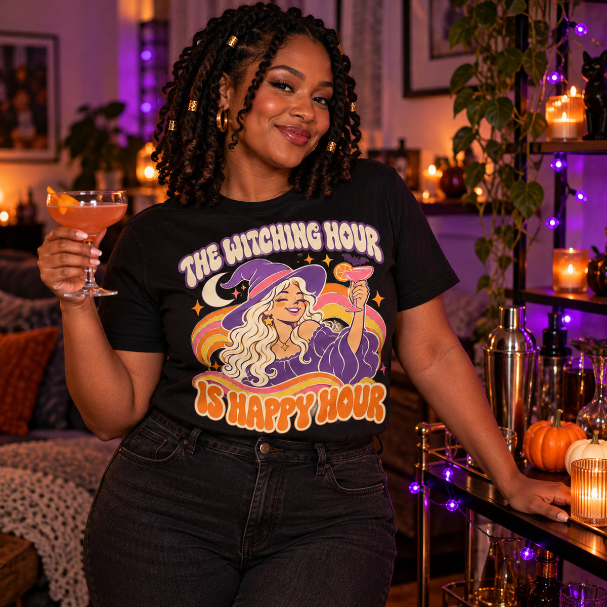 Woman wearing the Groovy Witch Cheers design black t-shirt holding a cocktail by a Halloween home bar cart