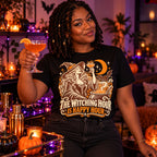 Woman wearing the Woodcut Witch Toast design black t-shirt holding a cocktail by a Halloween home bar cart