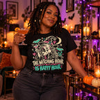 Woman wearing the Doodle Witch Happy Hour design black t-shirt holding a cocktail by a Halloween home bar cart