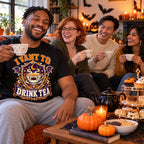 Friends wearing the Varsity Tea Crest design black t-shirt at a Halloween afternoon tea party with teapot and cakes
