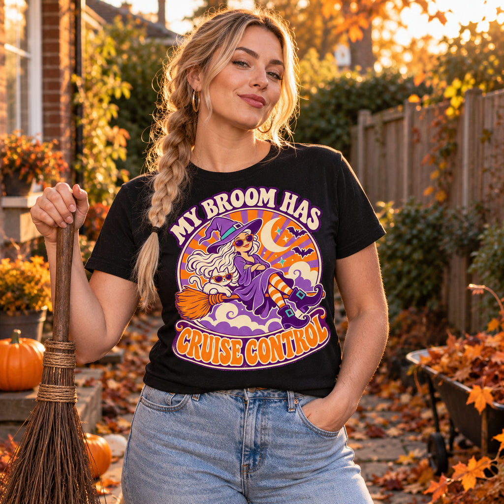 Woman wearing the Retro Witch Badge design black t-shirt holding a straw broom in an autumn garden with pumpkins