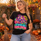 Woman wearing the Neon Witch Cruiser design black t-shirt holding a straw broom in an autumn garden with pumpkins