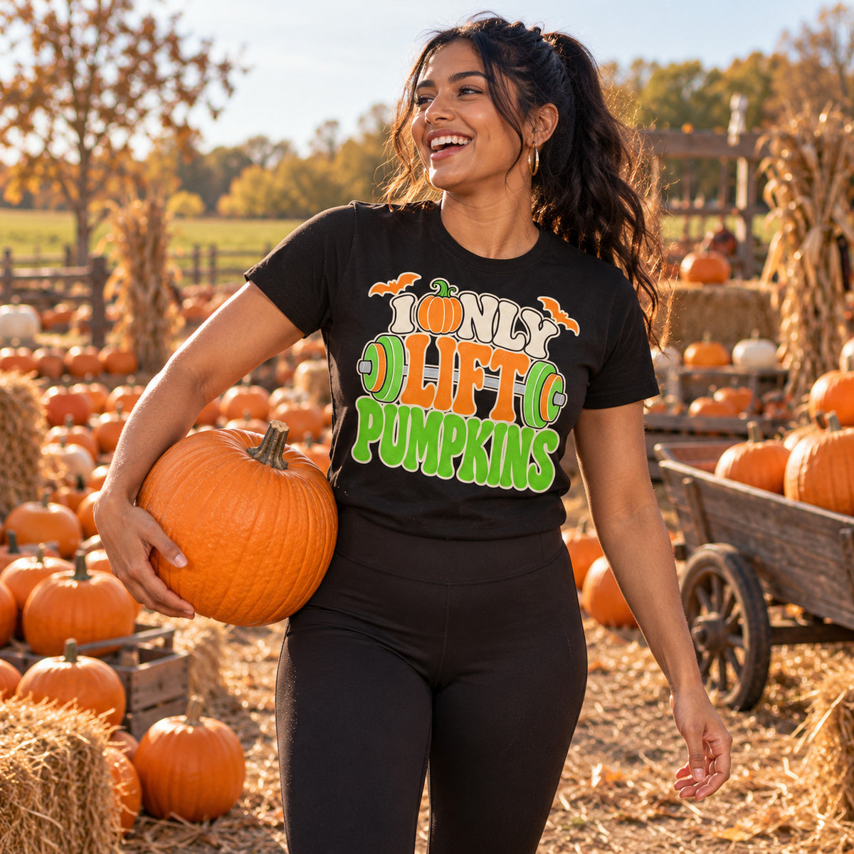 Woman wearing the Typography Barbell Letters design black t-shirt carrying a pumpkin at a pumpkin patch