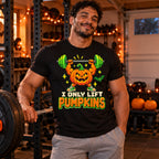 Man wearing the Pixel Powerlifter Pumpkin design black t-shirt in a home garage gym next to a barbell with pumpkins