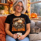 Woman wearing the Woodcut Coffin Cat design black t-shirt on a cosy window seat with a sleeping cat