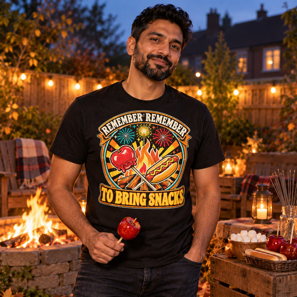 Man wearing the Retro Badge Bonfire Snacks design black t-shirt by his garden bonfire at dusk holding a toffee apple