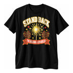 Black t-shirt with a varsity style gold sparkler starburst, fireworks and red banner with the text Stand Back I'm Holding A Sparkler