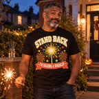 Man wearing the Varsity Sparkler Star design black t-shirt on his front garden path at dusk holding a sparkler