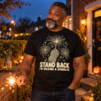 Man wearing the Line Art Mitten Sparkler design black t-shirt on his front garden path at dusk holding a sparkler