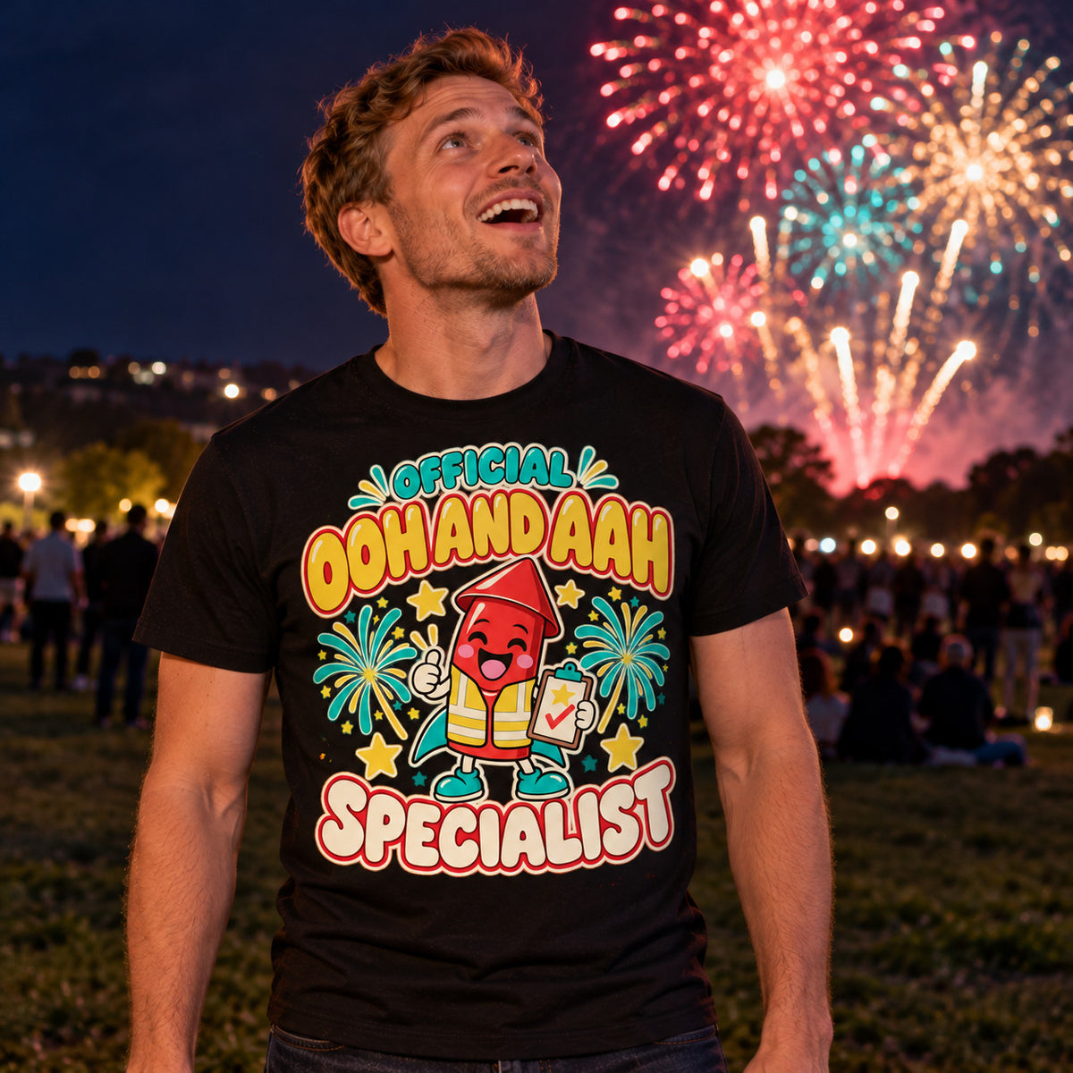 Man wearing the Cartoon Rocket Specialist design black t-shirt on a park hill at night looking up at fireworks
