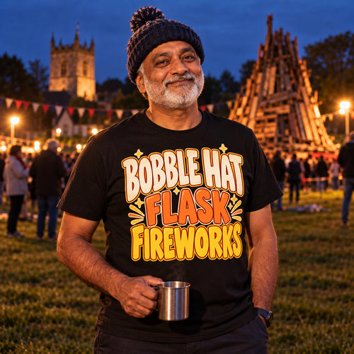 Man wearing the Bold Type Stack design black t-shirt on a village green at dusk holding a flask cup of tea