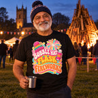 Man wearing the Groovy Wavy Trio design black t-shirt on a village green at dusk holding a flask cup of tea