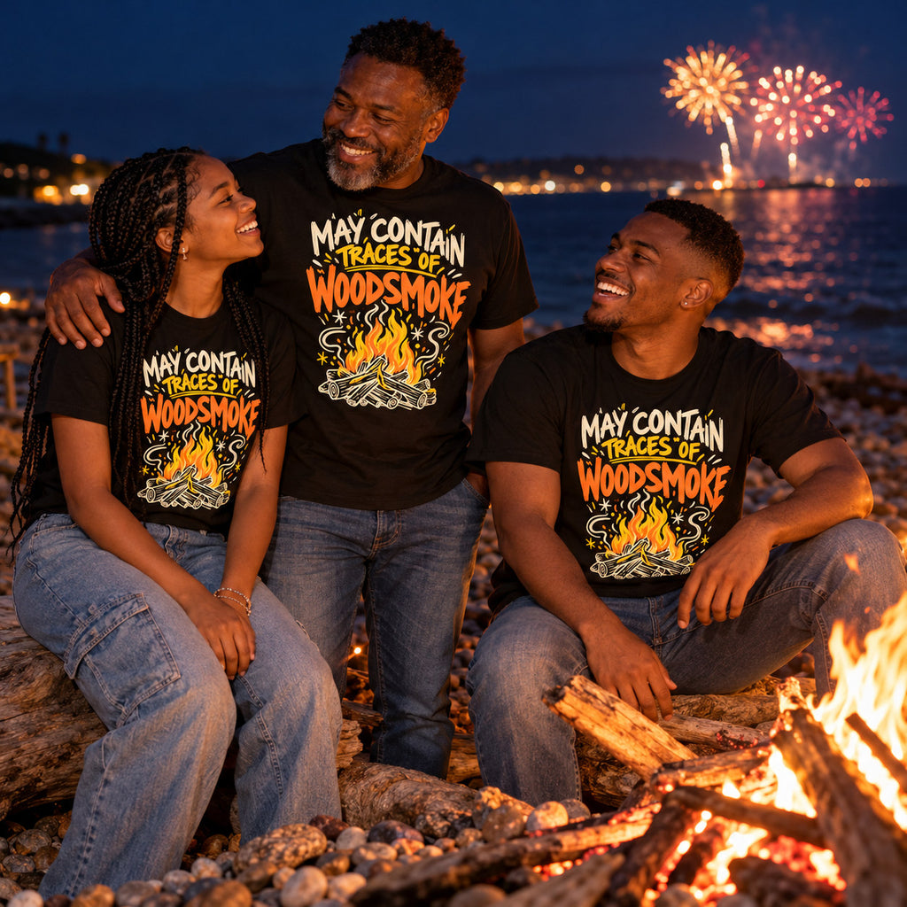 Family wearing matching Doodle Campfire design black t-shirts by a driftwood bonfire on a pebble beach at night