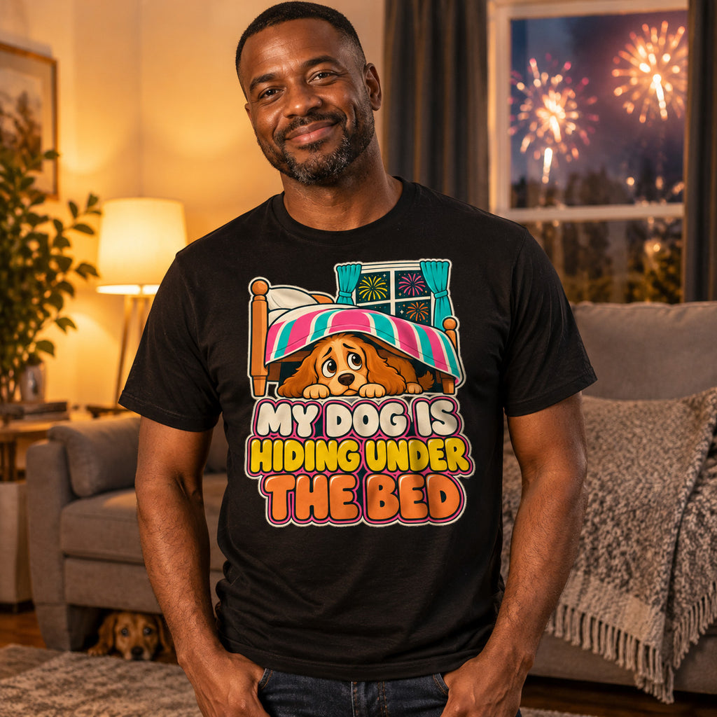 Man wearing the Cartoon Pup design black t-shirt in a cosy living room at night with a worried dog peeking out from under the sofa