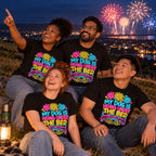 Four friends wearing matching Neon Pup design black t-shirts on a hillside at night watching fireworks over the town