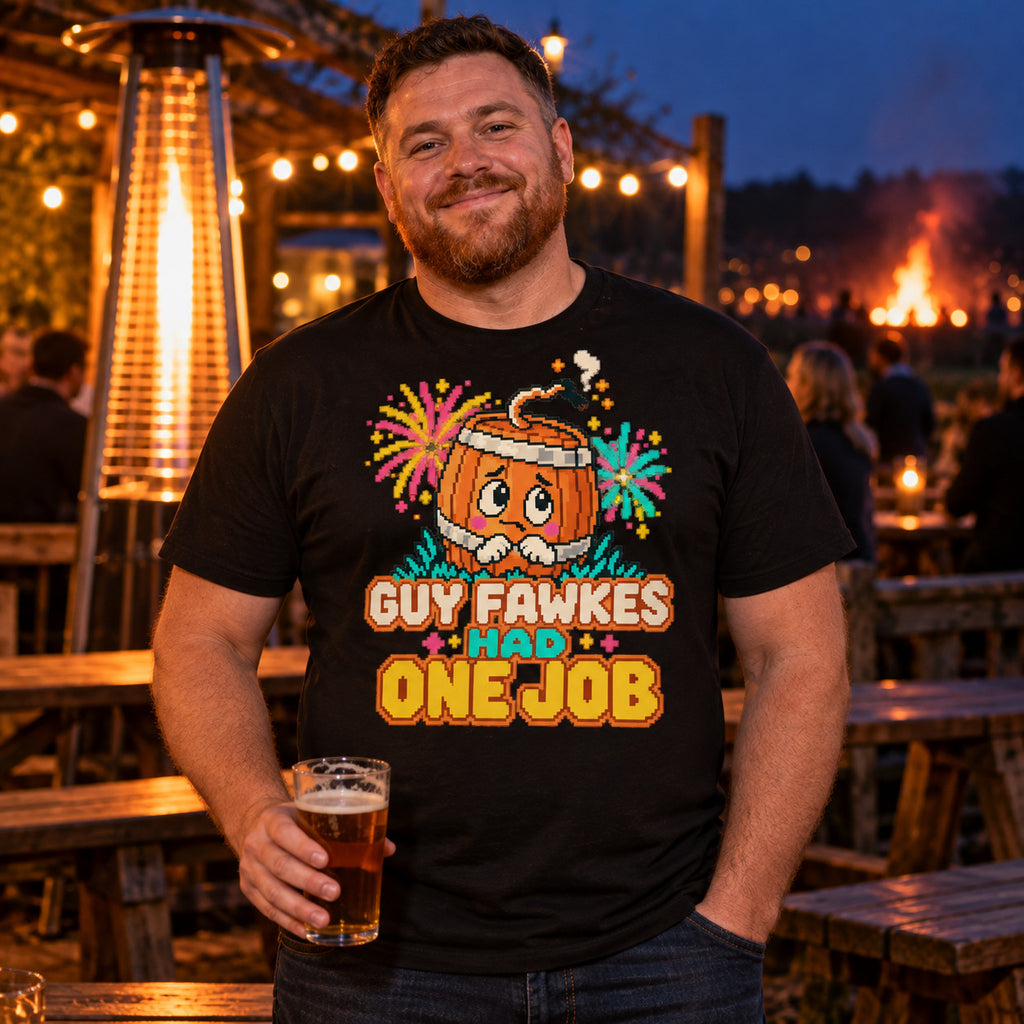 Man wearing the Pixel Barrel design black t-shirt in a pub beer garden at dusk holding a pint with a bonfire glowing behind