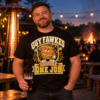 Man wearing the Varsity Barrel design black t-shirt in a pub beer garden at dusk holding a pint with a bonfire glowing behind