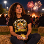 Woman wearing the Doodle Spud design black t-shirt sitting on a hay bale at a school field fireworks night holding a foil wrapped jacket potato