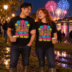 Couple wearing matching Neon Wellies design black t-shirts and wellington boots in a muddy riverside park at a fireworks night holding hot chocolates
