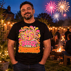 Man wearing the Groovy Wheel design black t-shirt in a UK back garden at dusk with fairy lights, a bonfire and fireworks behind