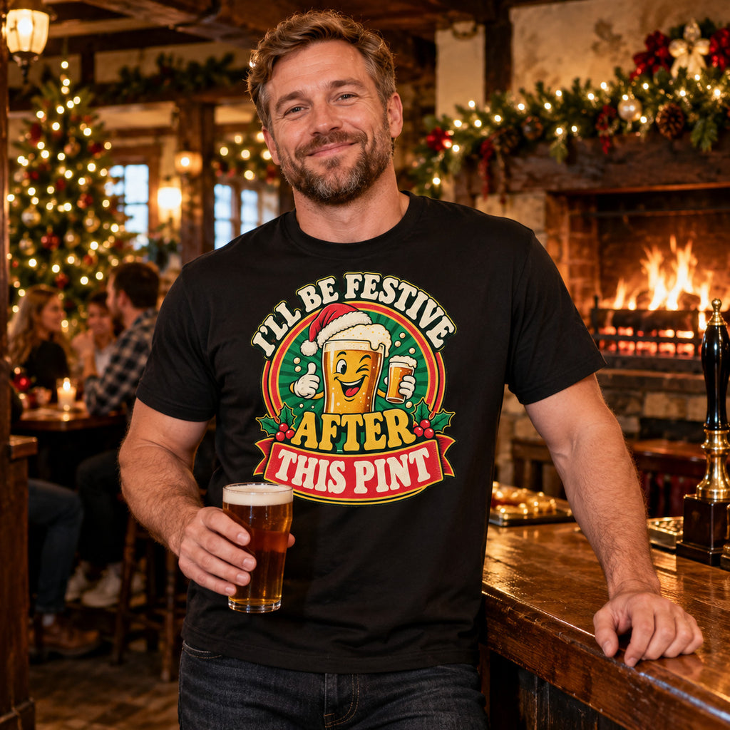 Man wearing the Pub Badge design black t-shirt at the bar of a cosy British village pub at Christmas with an open fire
