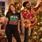 Woman wearing the Doodle Scribble design black t-shirt holding one bauble while her partner decorates the tree at home