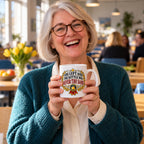 White mug with a gold laurel wreath, navy rosette and red ribbon reading You Left And The Kettle Was Never The Same, lifestyle photo 1