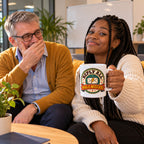 White mug with a round retro badge, lightning envelope and rust ribbon reading Reply All Was A Mistake, lifestyle photo 3