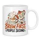 White mug with a teapot, cup, sugar cubes and terracotta and charcoal lettering reading Brew First, People Second