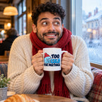 White mug with a shivering ice cube character in a red bobble hat and navy and blue lettering reading Too Cold For Meetings., lifestyle photo 1